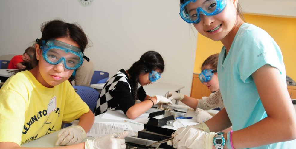 Students wearing googles and gloves dissecting a frog.