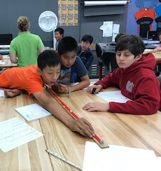 Three boys measuring distance with yardstick during forensic lesson.