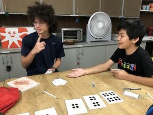 Two students using large cards with dots to learn binary.