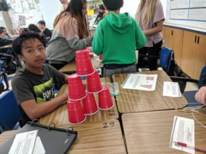 A student sits behind a pyramid of solo cups.