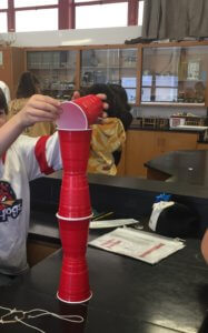 Students stack red solo cups on top of each other in a tower.