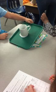 Students tilt a cup on a tray.