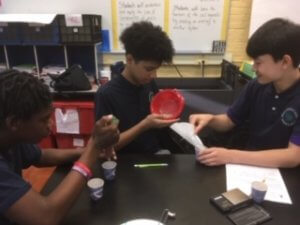 Three students work at a table to separate a mixture.