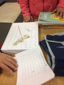 Students investigate magnetic items on a grid.