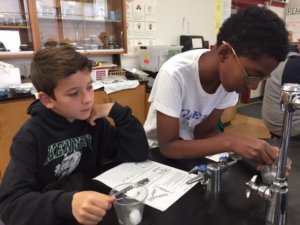 Student investigate dry ice in cups with metal spoons.