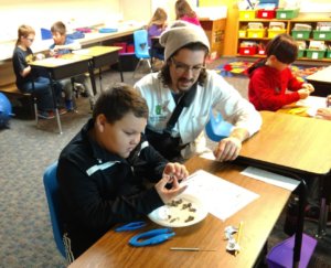 An instructor looks on as a student dissects an owl pellet.