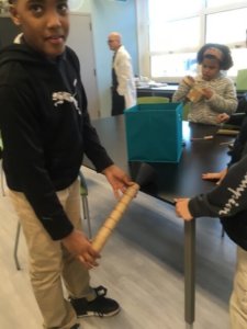 Students use a funnel and a tube as they build a Rube Goldberg device.