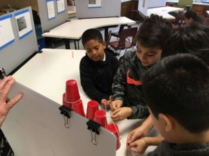 Students use a string tool to stack solo cups.