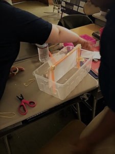 A plastic container is shown with a bridge being constructed inside it.