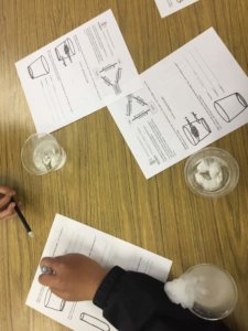 Cups with dry ice and worksheets are shown.