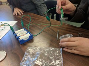 Students build electromagnets to pick up paperclips.