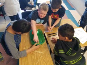 Students work in a group to construct a bridge with skewers.