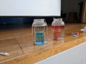 Two large containers with water are shown, one with blue water and one with red as part of the weather exploration.