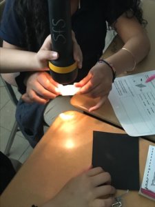 A student shines a flashlight on plexiglass.