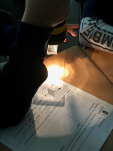 A student shines a flashlight on plexiglass.